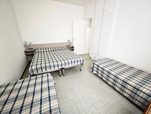 A dormitory room with three beds, a wardrobe, and a desk. - Cozy first-floor retreat near the sea (Lignano Sabbiadoro)