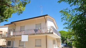 Un edificio residencial de varios pisos con balcones, una antena visible y una entrada portonada.