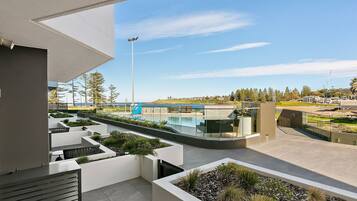 Uma área moderna com piscina ao ar livre e vista desobstruída para o mar, rodeada por jardins bem cuidados e arquitetura contemporânea.