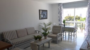 A living room with a sofa, chairs, a coffee table, and a balcony with a table and chairs. - Lovely 1-bedroom Apartment in Roquetas de Mar, Spain (Roquetas de Mar)