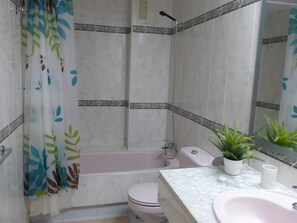 Ein Badezimmer mit Dusche, Toilette, Waschbecken und Spiegel.