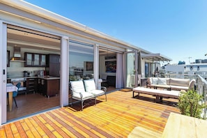 Eine moderne Terrasse mit Küchenbereich, Schiebetüren und Sitzgelegenheiten im Freien.