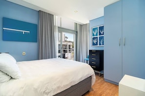 Ein Schlafzimmer mit Bett, Kleiderschrank, Schreibtisch und einem Fenster mit Vorhängen.