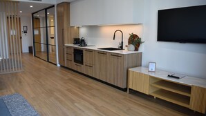 A modern kitchen with wooden cabinets, a black sink, and a built-in oven. - Kove Apartment - G05 (Kiama)