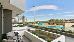A rooftop pool area with a view of the sea, outdoor seating, and a landscaped garden. - Kove Apartment - G05 (Kiama)