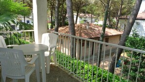 Un balcone con sedie e tavolo in plastica bianca, circondato da una ringhiera in metallo bianco.