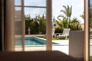 Une piscine entourée de chaises longues blanches et de plantes tropicales.