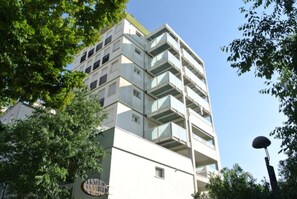 Ein mehrstöckiges Gebäude mit Balkonen, umgeben von Bäumen.
