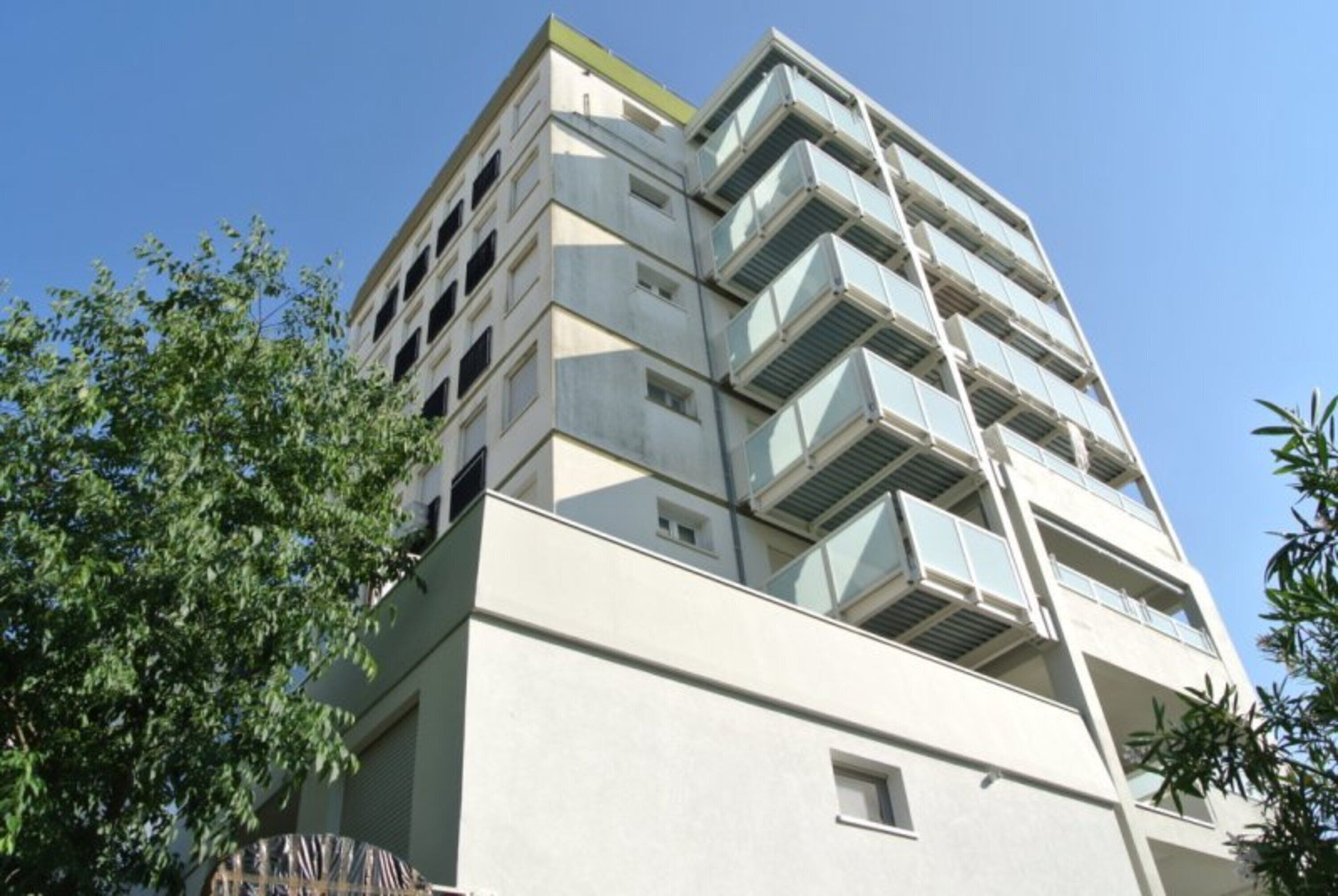Un immeuble à plusieurs étages, doté de balcons et d’une façade sobre, avec un ciel dégagé.