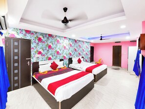 Una habitación de hotel con dos camas, un armario, un ventilador de techo y un papel tapiz floral.