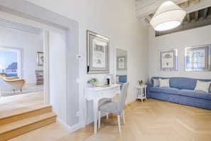 Ein modernes Interieur mit Schreibtisch, Stuhl, Sofa und gerahmten Kunstwerken an den Wänden.