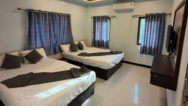 A hotel room with two beds, a ceiling fan, an air conditioning unit, and a television on the wall.