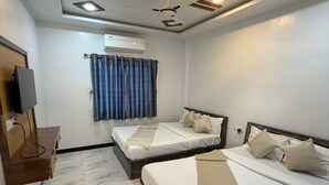 A hotel room with two beds, a ceiling fan, an air conditioning unit, a TV, and marble flooring.