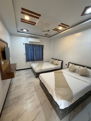 A hotel room with two beds, a ceiling fan, an air conditioning unit, a TV, and marble flooring. - Hotel Majestic Inn (Ellora)