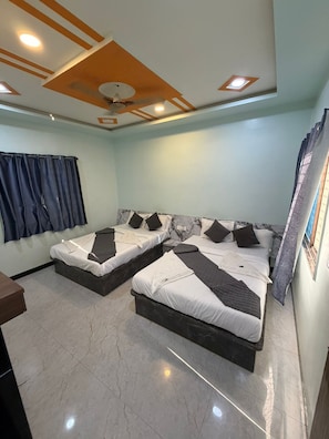 Ein Zimmer mit zwei Betten, einem Deckenventilator und einem fenster mit VorhÀngen.