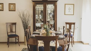Een eetkamer met een houten tafel voor zes personen, omringd door stoelen, een kast met glazen deuren en een scheepsmodel erboven.