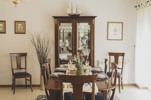 Ein Esszimmer mit Holztisch, gedeckt für sechs Personen, umgeben von Stühlen, einer Vitrine und einem Schiffsmodell darauf.