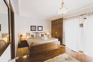 Ein Schlafzimmer mit einem großen Bett, einem Holzschrank, Nachttischlampen und einer Deckenleuchte.