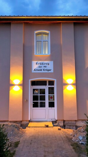 Ein Gebäude mit einem Schild über dem Eingang, auf dem 'Erbkrug' und 'Arnold Krüger' stehen.
