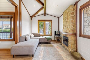 A cozy living room with a stone fireplace, a sofa, and a television.