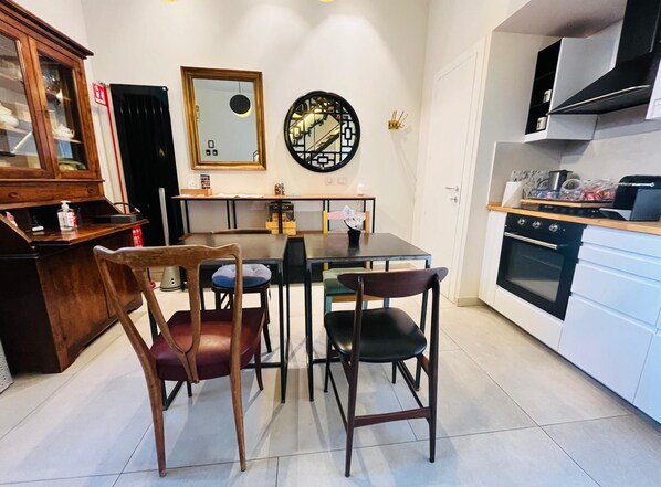 A modern kitchen with a dining table, chairs, a refrigerator, and a stove. - Torre Tolomei Trastevere (Rome)