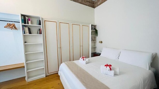 Un dormitorio con una cama grande, un armario con varias puertas y una estantería.