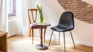 Una habitación con un muro de ladrillo circular, una mesa redonda con sillas, una ventana con cortinas y un radiador.