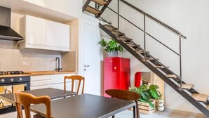 Una cocina moderna con una mesa de comedor y sillas, una escalera y un armario rojo.