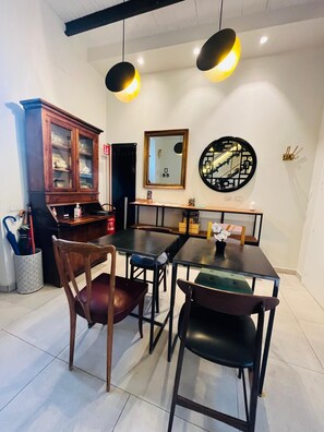 A dining area with a wooden cabinet, two pendant lights, a round mirror, and a table with chairs. - Torre Tolomei Trastevere (Rome)