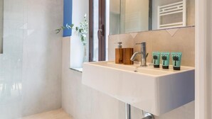 Un baño moderno con un espejo grande, un lavamanos y tres envases de artículos de aseo.