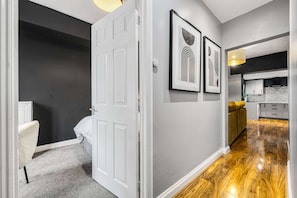A hallway with a white door, a bed, and a framed artwork on the wall. - 3 BR Home 3 min Close to MCR City Centre Free Park (Manchester)