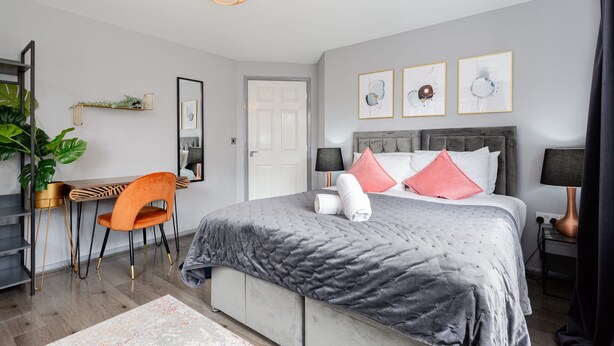 A modern bedroom with a bed, a desk, a chair, a plant, and artwork on the wall. - Trafford Centre Cityscape Hideaway Free Parking (Manchester)