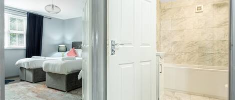 Ein Hotelzimmer mit Bett, einem Badezimmer mit Badewanne und einer Tür zu einem anderen Raum.