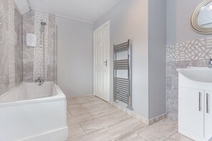 Ein modernes Badezimmer mit Badewanne, Dusche, Waschtisch und Handtuchhalter.
