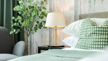 Ein ordentlich eingerichtetes Schlafzimmer mit einem Bett, Kissen, einer Nachttischlampe und einer kleinen Pflanze.