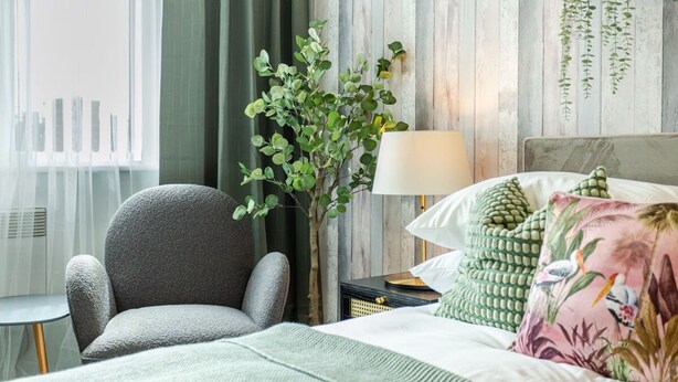 Ein Schlafzimmer mit Bett, Stuhl, Lampe und Pflanze.