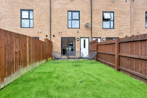 A courtyard with a brick building, a wooden fence, and three chairs. - Salford Quays Luxury Safari Retreat Free Parking (Salford)