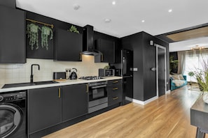 A modern kitchen with black cabinetry, a built-in oven, a microwave, and a sink. - Salford Quays Luxury Safari Retreat Free Parking (Salford)