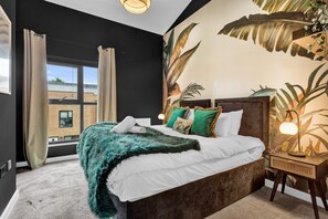 A bedroom with a large bed, a window with curtains, a wall mural, and a bedside lamp. - Salford Quays Luxury Safari Retreat Free Parking (Salford)