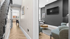 A modern living room with a flat-screen TV, grey sofa, and a dining area with a table and chairs. - Sleeps 14 The Old Trafford Zen by Genesis Living (Manchester)