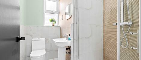 Een badkamer met toilet, wastafel en douche.