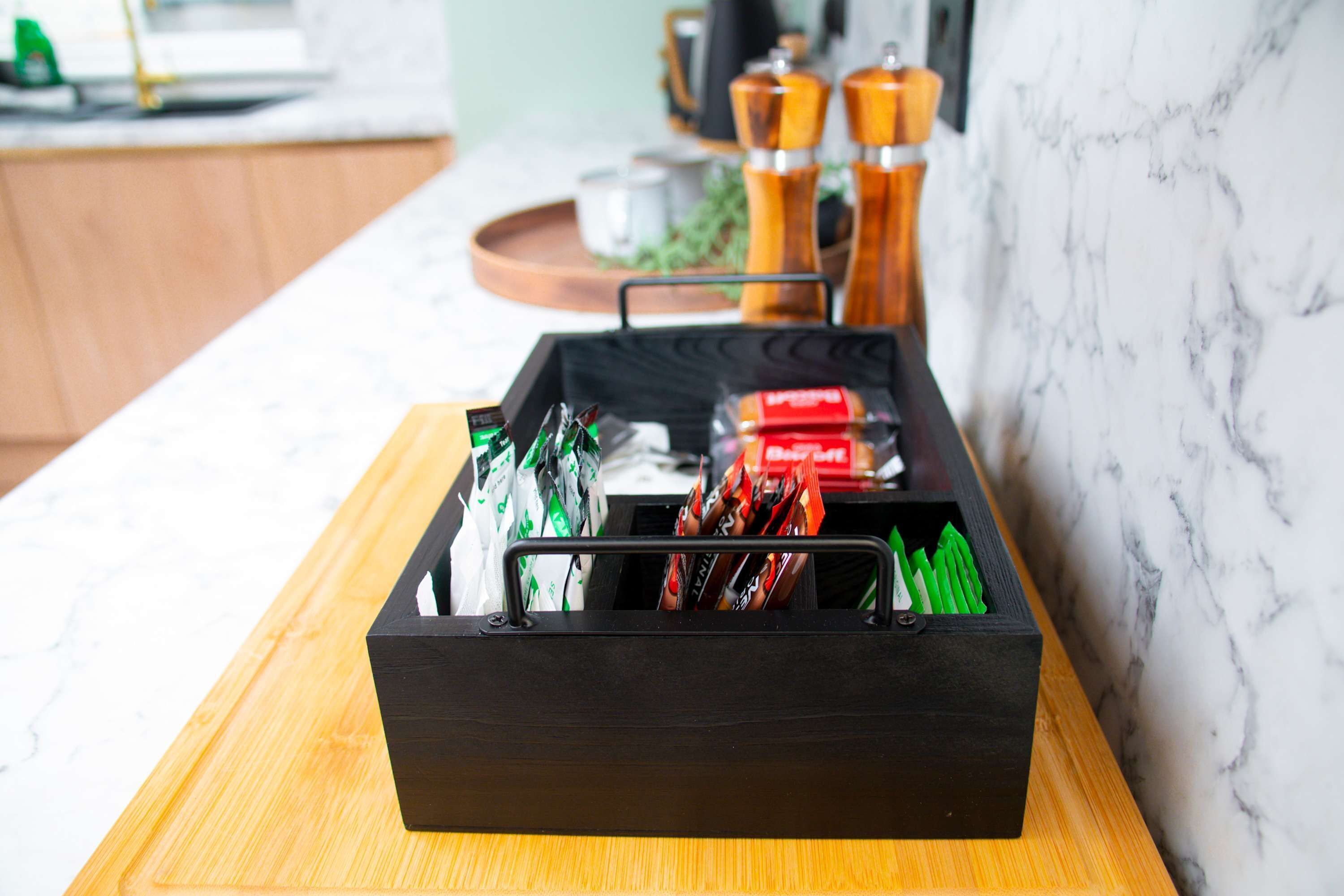 A kitchen counter with a black storage box containing various food items.