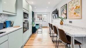 A modern kitchen with marble countertops, stainless steel appliances, and a dining area with bar stools. - 2 Free Park Space The Quays- Sleeps 8 2 Ensuites (Salford)