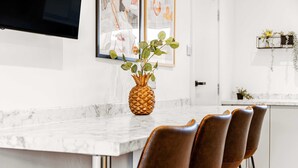 A kitchen with a marble countertop, a pineapple centerpiece, and brown chairs. - 2 Free Park Space The Quays- Sleeps 8 2 Ensuites (Salford)