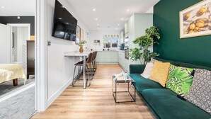 A modern living room with a green sofa, a coffee table, and a TV mounted on the wall. - 2 Free Park Space The Quays- Sleeps 8 2 Ensuites (Salford)