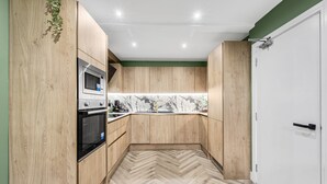 Una cocina con armarios de madera, un microondas y un piso con diseño de espiga.