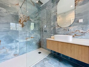 A modern bathroom with a glass shower enclosure, a wooden vanity, and a marble backsplash. - Recanto do Sol by Atlantic Holiday (Machico)