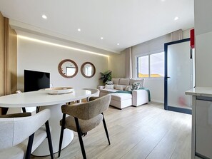 Ein modernes Wohnzimmer mit einer Couch, einem Esstisch mit Stühlen und einem Fernseher.