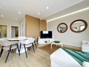 Ein modernes Wohnzimmer mit Essbereich, einem Flachbildfernseher und zwei Wandspiegeln.