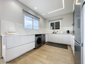 Eine moderne Küche mit Einbauwaschmaschine, großem Fenster und Edelstahlkühlschrank.